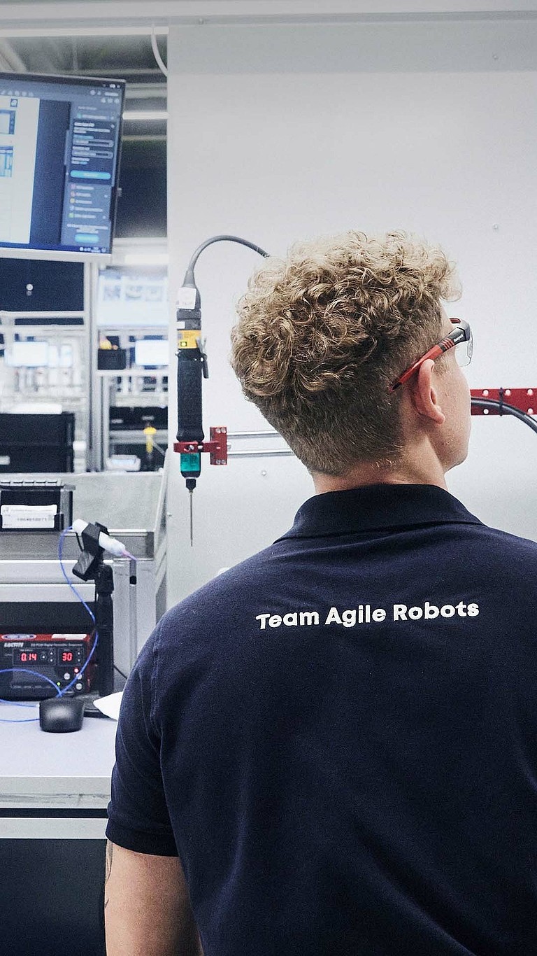 Ein Mitarbeiter von Agile Robots prüft die Qualität eines Bauteils am Produktionsstandort Kaufbeuren