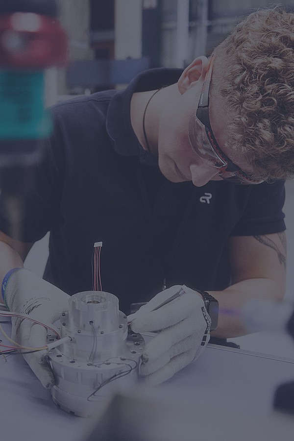 An Agile Robots employee working on a component with precision, inspecting for quality.